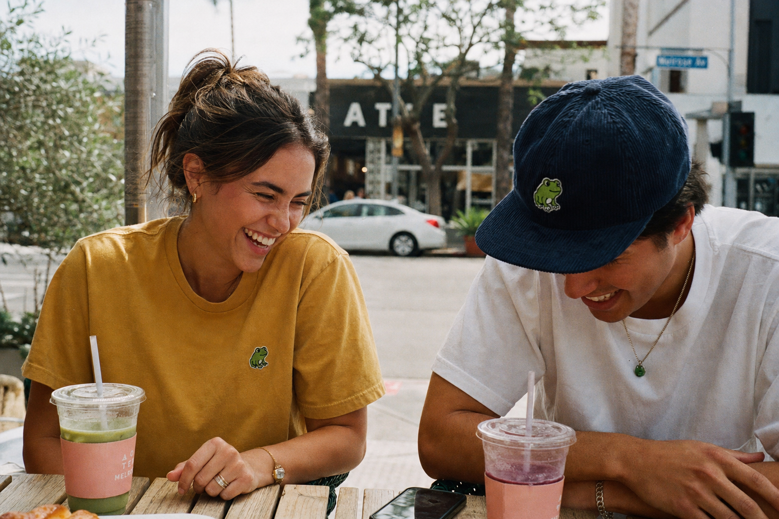 Lifestyle — mustard tee and navy hat at cafe